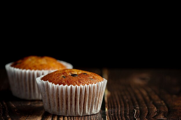 Deux muffins au chocolat mis sur un plancher en bois