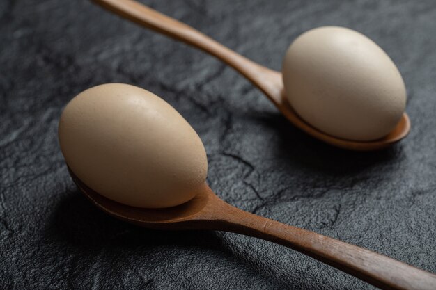 Deux œufs de poule frais sur des cuillères en bois.