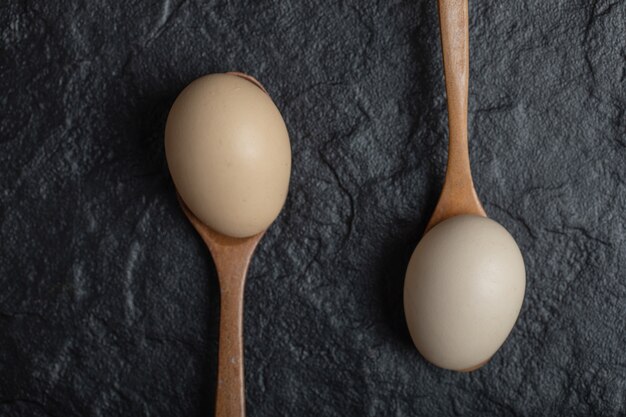 Deux œufs de poule frais sur des cuillères en bois.