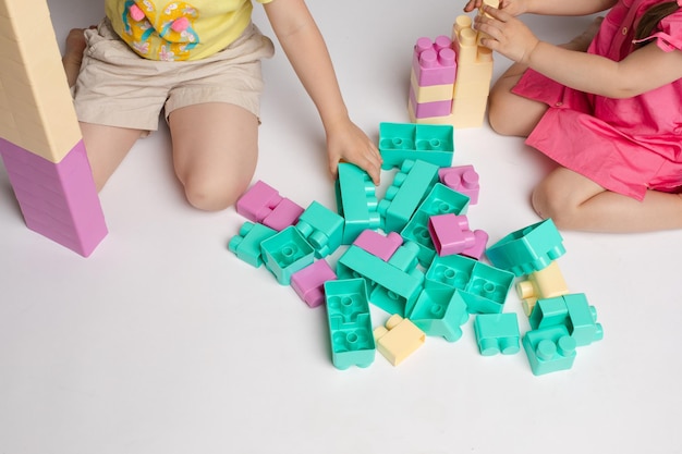 Deux Petites Filles Enthousiastes Jouant Au Constructeur D'assemblage Plein Coup Sur Fond Blanc De Studio