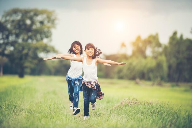 Deux petites filles mignonnes courent sur l&#39;herbe verte. Meilleurs amis.