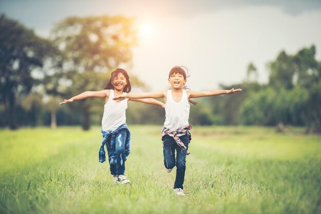 Deux petites filles mignonnes courent sur l&#39;herbe verte. Meilleurs amis.