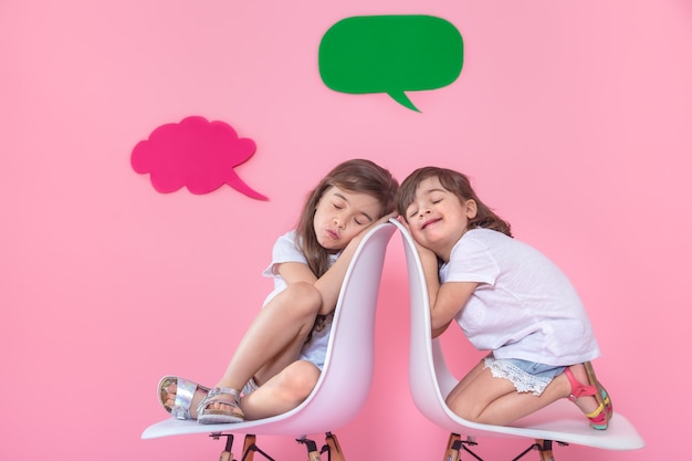 Deux petites filles sur un mur coloré avec des icônes de discours