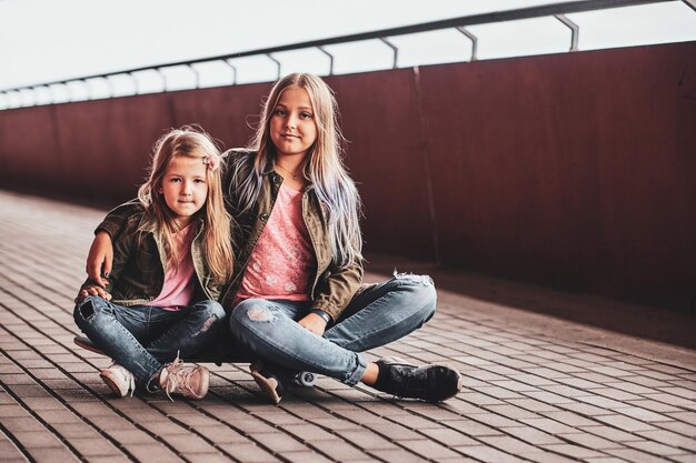 Deux petites soeurs joyeuses sont assises sur la planche à roulettes dans le tunnel.