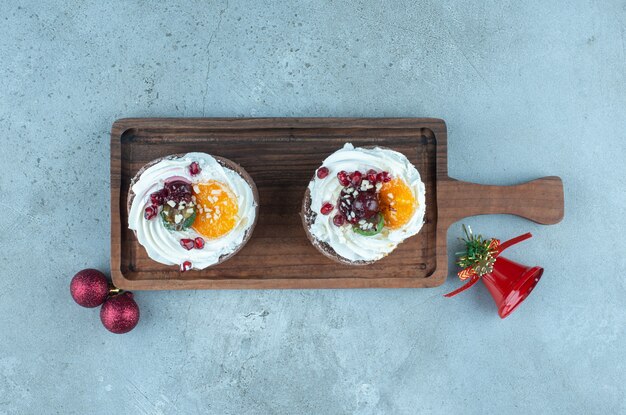 Deux petits gâteaux sur un plateau en bois sur marbre.