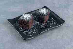 Photo gratuite deux petits morceaux de brownie sur une assiette sombre