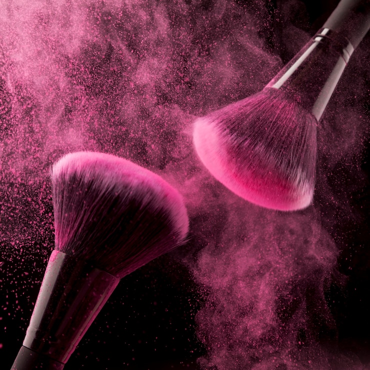 Photo gratuit deux pinceaux de maquillage et poudre rose sur fond sombre