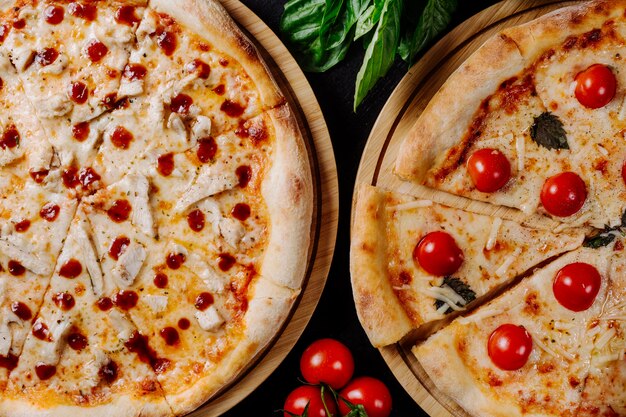 Deux pizzas différentes avec des tomates cerises et du pepperoni.