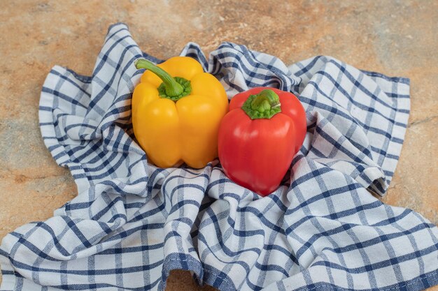 Deux poivrons colorés allongés sur une nappe