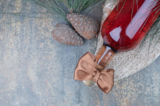 Deux pommes de pin avec une bouteille de vin sur une table en marbre.