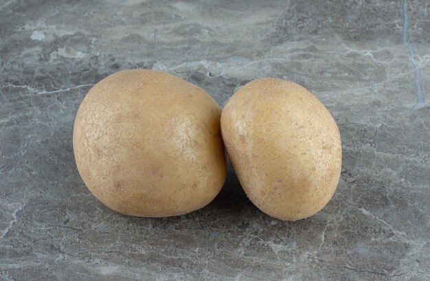 Deux pommes de terre mûres , sur la table en marbre.