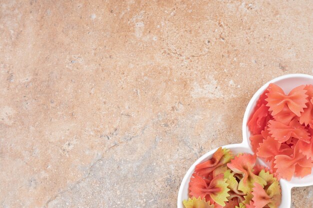 Photo gratuite deux portions de pâtes farfalle s'incline sur une assiette blanche .