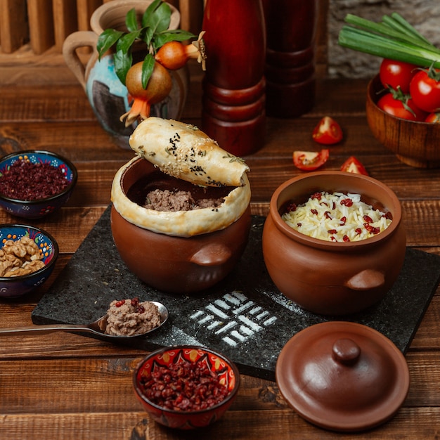 Photo gratuite deux pots de poterie avec du riz et de la viande hachée recouverte de pâte sablée