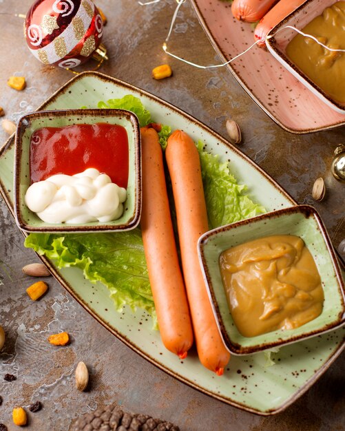 Deux saucisses sur la table avec du ketchup et de la moutarde