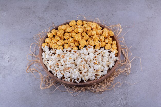 Deux saveurs de pop-corn servies sur un plateau en bois décoré de paille sur fond de marbre. photo de haute qualité