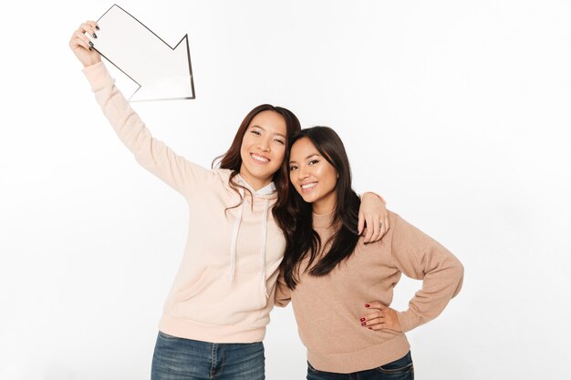 Deux soeurs asiatiques dames positives tenant la flèche.