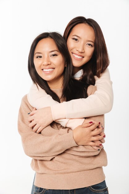 Deux soeurs asiatiques très souriantes mesdames étreignant