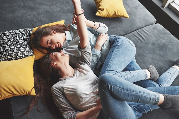 Deux soeurs jumelles souriantes mignonnes tenant un smartphone et faisant selfie.