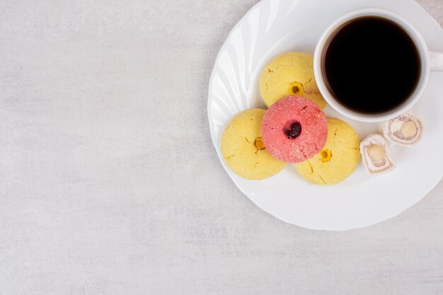 Deux sortes de biscuits, délices et tasse de thé sur une assiette blanche.