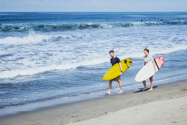 Deux surfeurs marchant le long du rivage