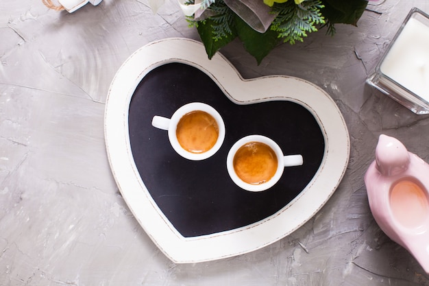 Deux tasses blanches d'espresso sur le plateau de coeur de tableau