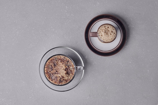 Deux tasses de cappuccino sur fond gris.