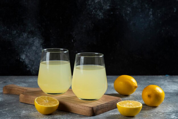 Deux tasses de jus de citron sur planche de bois.