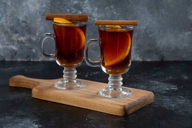 Deux tasses en verre avec du thé frais et des bâtons de cannelle.