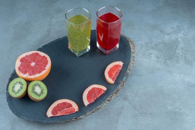 Deux tasses en verre de jus de fruits frais avec des tranches de fruits divers.