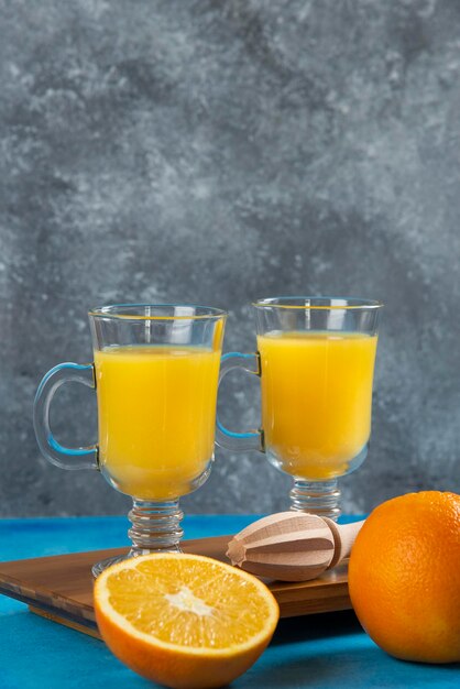 Deux tasses en verre de jus d'orange sur planche de bois.