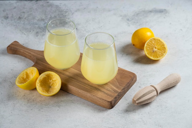 Deux tasses en verre de limonade sur une planche de bois.