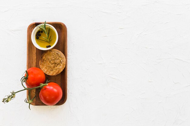 Deux tomates avec du pain et de l&#39;huile de poivre noir sur un plateau en bois