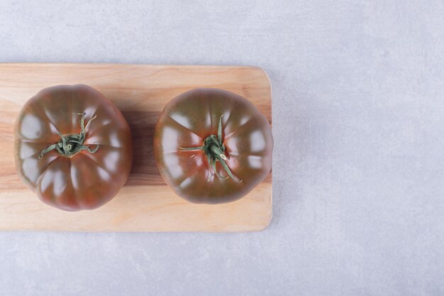 Deux tomates mûres sur planche de bois.