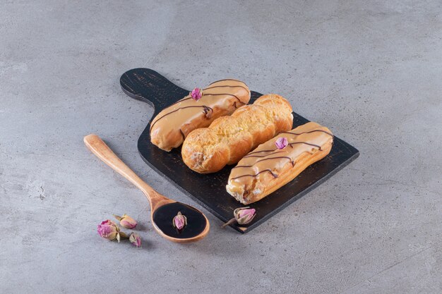 Deux types d'éclairs au chocolat avec une cuillère de chocolat sur la surface de la pierre.