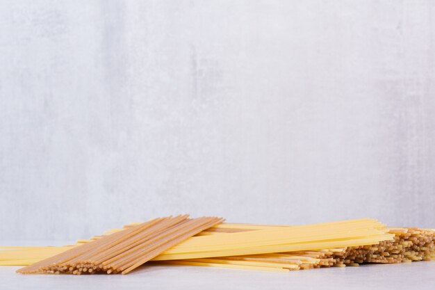 Deux types de pâtes spaghetti crues sur une surface blanche