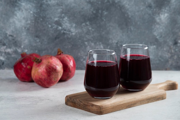 Deux verre d'un jus de grenade rouge sur planche de bois.