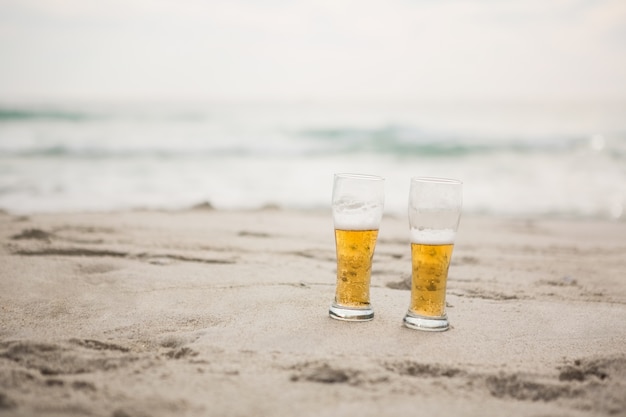 Deux verres de bière conservés sur le sable