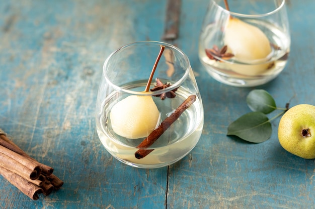 Photo gratuite deux verres avec une boisson avec des poires sucrées cuites dans du vin blanc sur une table en bois dessert festif