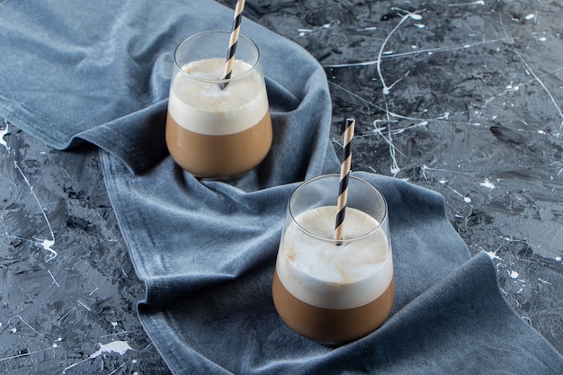 Deux verres de café froid avec du lait sur une surface en marbre.