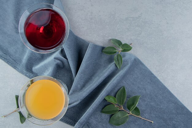 Deux verres de jus et de feuilles sur une serviette, sur le fond de marbre. Photo de haute qualité