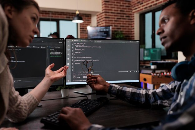 Les développeurs de réseau mettent à jour le système de pare-feu grâce au traitement de l'information à l'aide de plusieurs couches de sécurité. Les programmeurs de l'entreprise se tiennent près du bureau avec plusieurs moniteurs dessus.