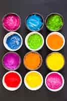 Photo gratuite différentes couleurs de poudre de couleur holi dans les bols sur fond noir