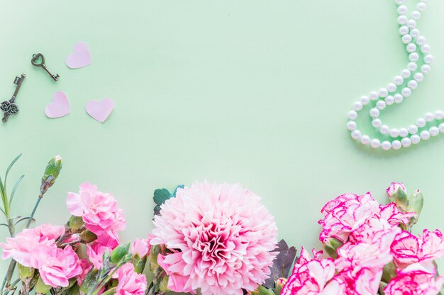 Différentes fleurs roses avec des coeurs sur la table verte
