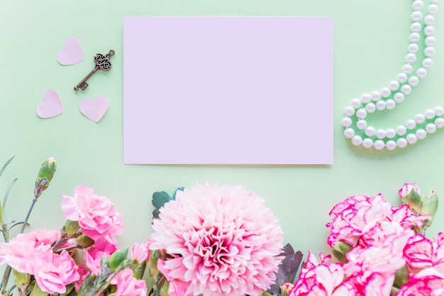 Différentes fleurs roses avec du papier sur la table verte