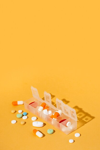 Différentes pilules sur fond jaune