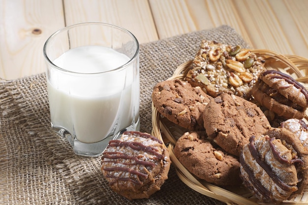 Différents biscuits et un verre de lait pour le petit déjeuner sur une table en bois