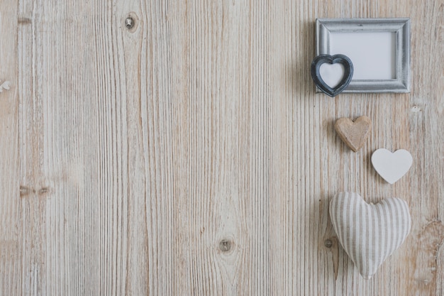 Photo gratuite différents coeurs et un cadre blanc sur une table en bois