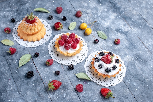 Différents gâteaux crémeux avec des baies et des fruits frais sur un biscuit aux fruits frais aux baies