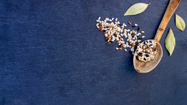 Différents grains de riz à la cuillère en bois sur la table bleue