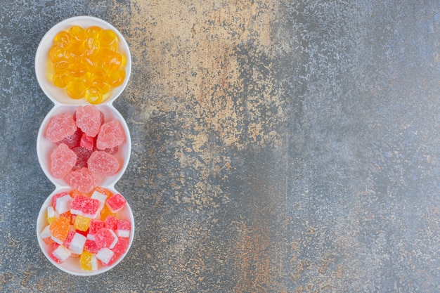 Différents types de bonbons à la gelée sucrée dans des assiettes blanches. Photo de haute qualité